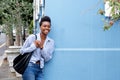 Smiling young woman leaning against wall with bag Royalty Free Stock Photo