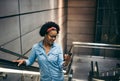 Smiling young woman listening to music riding up an escalator Royalty Free Stock Photo