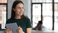 Smiling young woman looking aside while working at digital pad