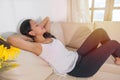 Smiling young woman lying on comfortable couch hands over head relaxing on sunny weekend at home Royalty Free Stock Photo