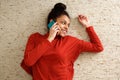 Smiling young woman lying on floor and talking on cell phone Royalty Free Stock Photo