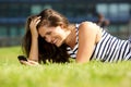 Smiling young woman lying on grass using mobile phone Royalty Free Stock Photo