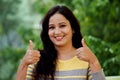 Smiling young woman making thumb up gesture at outdoors Royalty Free Stock Photo