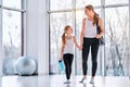 Smiling young woman and man with spots bag and mat wearing sportswear and chatting while walking in corridor of fitness center