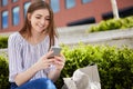 Smiling Young Woman With Mobile Phone Checking Social Media Outside Office