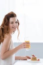 smiling young woman with orange juice and pancakes with strawberry for breakfast looking