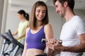 Smiling young woman and personal trainer with dumbbells in gym Royalty Free Stock Photo