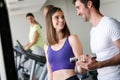 Smiling young woman and personal trainer with dumbbells in gym Royalty Free Stock Photo