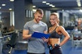 Smiling young woman with personal trainer in gym Royalty Free Stock Photo