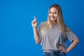 Smiling young woman pointing at copy space over blue background Royalty Free Stock Photo