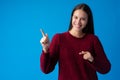 Smiling young woman pointing at copy space over blue background Royalty Free Stock Photo