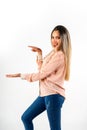 Smiling young woman pointing with one hand to the white space while with the other outstretched hand pretending to hold a product Royalty Free Stock Photo