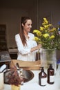 Smiling young woman putting flowers in a vase at home Royalty Free Stock Photo