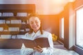 Smiling young woman reading book in home library Royalty Free Stock Photo