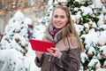 Smiling young woman reading on a tablet in the winter on the street