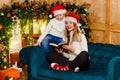 Smiling young woman in red socks and boy sitting on sofa with book near Christmas fireplace, mother and son Royalty Free Stock Photo