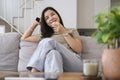 Smiling young woman relaxing on comfortable sofa, enjoying watching television at home Royalty Free Stock Photo