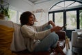 Smiling young woman relaxing on couch at home holding tv remote control Royalty Free Stock Photo