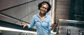 Smiling young woman riding up an escalator listening to music Royalty Free Stock Photo