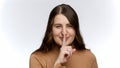 SMiling young woman saying hush and putting finger at lips. Concept of keeping secret and silence