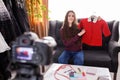 Smiling young woman shooting clothing review video, sitting on couch at home, speaking Royalty Free Stock Photo