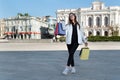 Smiling young woman with shopping bags on city background . Girl tourist with souvenirs and gifts in hands Royalty Free Stock Photo