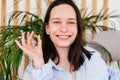 Smiling young woman with short hair holding pill omega capsule in hand at home. Girl taking medicine indoors Royalty Free Stock Photo