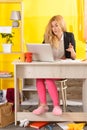 Smiling young woman sit at desk work on laptop or watching webinar making notes in notebook Royalty Free Stock Photo