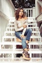 Smiling young curly latin woman sits on stairs. urban scene Royalty Free Stock Photo