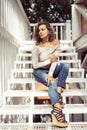 Smiling young curly latin woman sits on stairs. urban scene Royalty Free Stock Photo