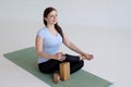 Smiling young woman sitting in Ardha Padmasana with props for hip opening,