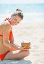 Smiling young woman sitting on beach with coconut Royalty Free Stock Photo