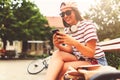 Smiling young woman sitting on a bench in the summer using smart phone Royalty Free Stock Photo