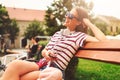 Smiling young woman sitting on a bench in the summer using smart phone Royalty Free Stock Photo