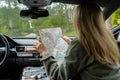 Smiling young woman sitting in car on road check the route on travel map. Local solo travel on weekends concept. Exited Royalty Free Stock Photo