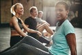 Smiling young woman sitting with friends on a gym floor Royalty Free Stock Photo