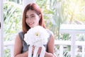 Smiling young woman sitting in the garden holding bouquet of white flowers happily. Cheerful girl black long hair Royalty Free Stock Photo