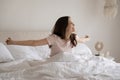Smiling young woman sitting with hands outstretched in cozy bed Royalty Free Stock Photo