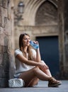 Woman sitting near old stone wall drinking water Royalty Free Stock Photo