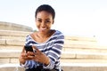 Smiling young woman sitting outside using cellphone Royalty Free Stock Photo