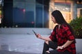 Young woman sitting on stairs in city at night and using smart phone. Royalty Free Stock Photo