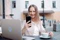 smiling young woman sitting at a table in an outdoor cafe. Royalty Free Stock Photo