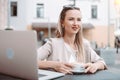 smiling young woman sitting at a table in an outdoor cafe. Royalty Free Stock Photo