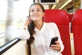 Smiling young woman sitting in train using cellphone Royalty Free Stock Photo