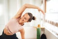 Smiling young woman in sports clothing doing side bending exercise at home Royalty Free Stock Photo