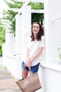 Smiling young woman standing against wall with bag Royalty Free Stock Photo