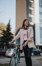 Smiling young woman standing with her bicycle in the city Royalty Free Stock Photo