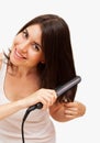 Smiling young woman straightening her hair