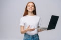 Smiling young woman student holding laptop and looking at camera on isolated gray background. Royalty Free Stock Photo