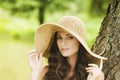 Smiling young woman in sun hat against background of summer green park. Beautiful healthy happy girl enjoying freedom outside Royalty Free Stock Photo